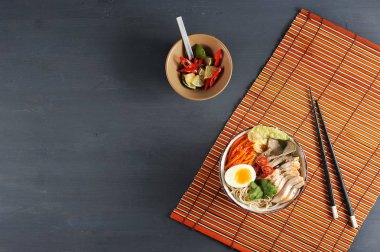 Derin bir kapta erişte. Erişte yapısı tavuk göğsü, mantar, havuç, yumurta, biber, kişniş, susam içerir. Çerçeveiçinde, çubukları, kireç ve biber ile sos. Yukarıdan görüntüle.