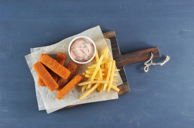 Balık, tahta bir tahtada ekmekli ve patates kızartması na yapışır. Sırada 