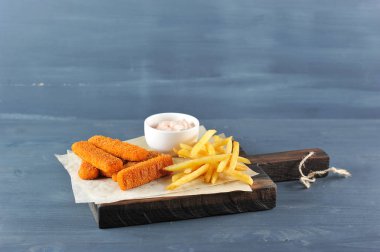 Balık, tahta bir tahtada ekmekli ve patates kızartması na yapışır. Sırada 