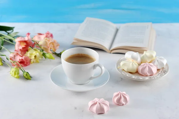 Sweet dreams ... A book, a cup of coffee, meringue, flowers. Romantic and gentle compassion. Light background. Close-up.