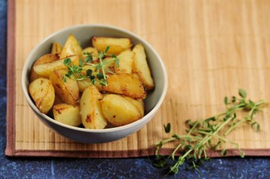 Derin bir kapta kızarmış patates dilimleri. Patates yeşil bezelye filizi ile desteklenir. Arka plan bambudan yapılmış bir peçete. Close. 