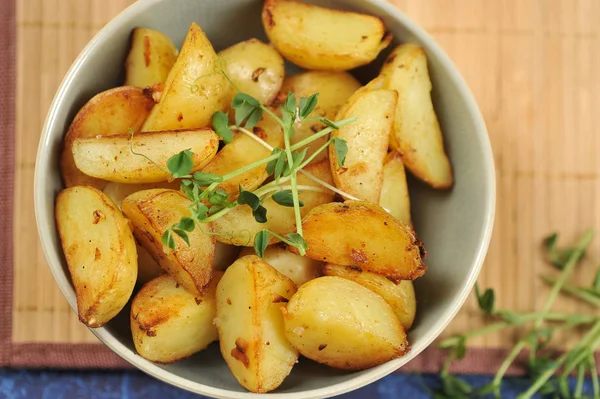 Derin bir kapta kızarmış patates dilimleri. Patates yeşil bezelye filizi ile desteklenir. Arka plan bambudan yapılmış bir peçete. Close. Yukarıdan görüntüleyin. Makro fotoğrafçılık.