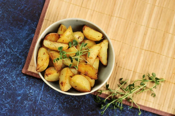 Derin bir kapta kızarmış patates dilimleri. Patates yeşil bezelye filizi ile desteklenir. Arka plan bambudan yapılmış bir peçete. Close. Yukarıdan görüntüle. 