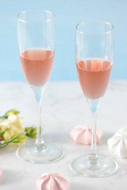 Pembe şaraplı iki bardak. Çerçeve çiçek ve açık pembe renklerde beze. Açık arka plan. Close. Çerçevenin dikey yönü.