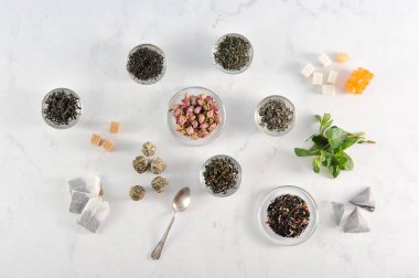 Çeşitli çay. Çerçevesiyah büyük yaprak çay, yeşil, yasemin ile yeşil, sütlü oolong, aromalı, topları çay. Nane taze, kurutulmuş çiçek tomurcukları, şeker, çay poşetleri ... Yukarıdan görüntüle.