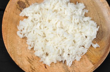 Yuvarlak tahta bir tabakta haşlanmış pirinç. Yukarıdan görüntüleyin. Karanlık arka plan. Close. Makro fotoğrafçılık.