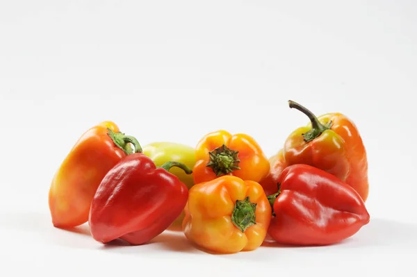 Multicolored sweet pepper on a white background. In a pile of pepper red, yellow, green, orange. Close-up.Multicolored sweet pepper on a white background. In a pile of pepper red, yellow, green, orange. Close-up.