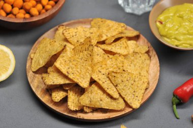 Tahta bir tabakta mısır cipsi nachos. Guacamole soslu bir sonraki kase. Gri arka plan. Yukarıdan görüntüleyin. Close. Makro fotoğrafçılık.