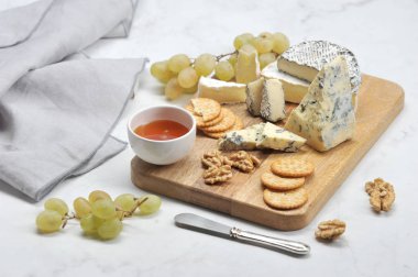 Hafif bir arka plan üzerinde peynir tabağı. Küf dorblu ile peynir bir tabak üzerinde, kül, brie, kraker, yeşil üzüm, bal ve ceviz camembert. Close. 