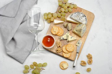 Peynir kalıp dorblu, kraker, bal, üzüm, brie, camembert hafif ahşap tahta üzerinde. Bir çerçeve peçete, şarap için bir bardak ve peynir için bir bıçak. Beyaz arka plan. Close. Yukarıdan görüntüle.
