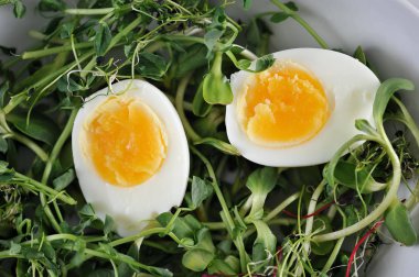 Çanak, bezelye, ayçiçeği ve yumuşak haşlanmış yumurta iki yarısı lahanası. Çerçeve çatal ve zeytinyağı bir şişe. Açık arka plan. Yukarıdan görüntüleyin. Close.