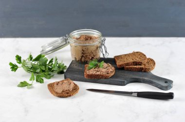 Tahta bir tahtada, ciğer pate ile siyah ekmek birkaç dilim. Pate ile cam bir kavanoz yanında. Close.