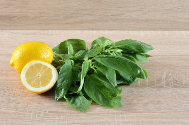 Fesleğenyeşil bir demet, yarım limon ve bir bütün limon vardır. Açık ahşap arka plan. Close. Makro fotoğrafçılık.