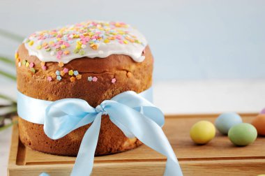 Tahta bir tahtada Paskalya pastası. Pasta mavi ipek kurdele ile bağlıdır. Çerçeve içinde yumurta şeklinde renkli çikolata tatlılar vardır. Açık arka plan. Close. Makro fotoğrafçılık.