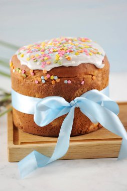 Tahta bir tahtada Paskalya pastası. Pasta mavi ipek kurdele ile bağlıdır. Çerçevenin dikey yönü. Açık arka plan. Close. Makro fotoğrafçılık.