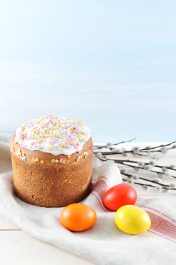 Bez peçeteüzerine Paskalya pastası. Tavuk yumurtaları etrafında kırmızı, sarı ve turuncu. Söğüt dalı çerçevesinde. Açık ahşap arka plan. Close. Çerçevenin dikey yönü.