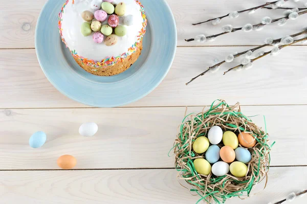 Tabakta Paskalya pastası. Çerçevede, söğüt dalları ve kağıt şeritler bir yuva, bir kuş yuvası taklit. Yuvada yumurta şeklinde tatlılar vardır. Açık arka plan. Yukarıdan görüntüle.