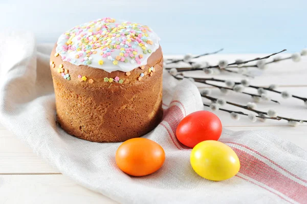 Bez peçeteüzerine Paskalya pastası. Tavuk yumurtaları etrafında kırmızı, sarı ve turuncu. Söğüt dalı çerçevesinde. Açık ahşap arka plan. Close. 