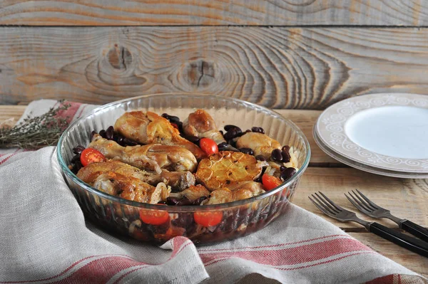 Derin bir cam çanak fasulye ve domates ile Tavuk. Bir sonraki çatal bıçak takımı ve tabaklar. Çerçeve peçete bezyapılmış. Ahşap arka plan. Close. 