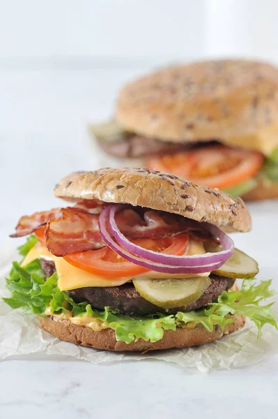Sığır köftesi ve kızarmış pastırma ile hamburger. Dolgu peynir, salatalık turşusu, domates, marul, soğan ve sos bir dilim oluşur. Çerçevenin dikey yönü. Close.