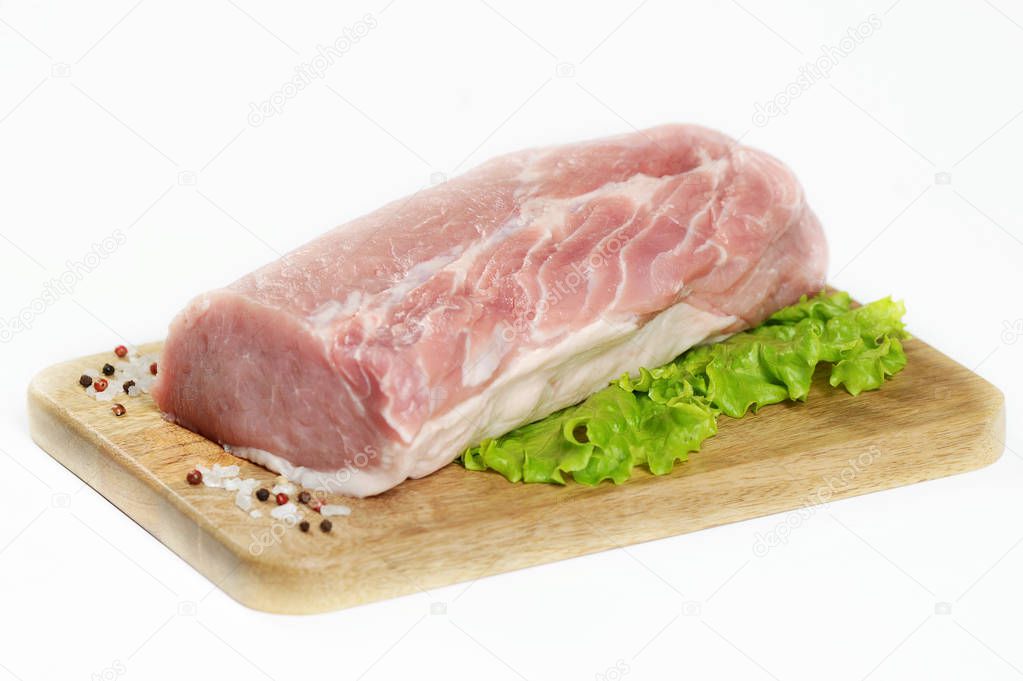 A piece of raw meat on a wooden board. A piece of pork carbonate for steaks. White background. Close-up. 