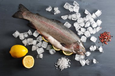 Somon Atlantik çiğ, harcanmış. Balığın karnı limon dilimleri ile doldurulr. Buz küpleri, baharatlar, limon. Koyu ahşap arka plan. Yukarıdan görüntüleyin. Close.