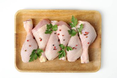 Hafif ahşap tepside çiğ tavuk baget. Tavuk bacakları maydanoz ve baharatlarla süslenmiştir. Beyaz arka plan. Yukarıdan görüntüleyin. Close.