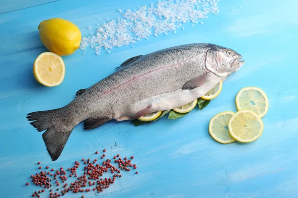Atlantik büyük somon. Kafası olan somon balığı, harcanmış. Balık yanında limon ve bireysel dilimler vardır. Tuz ve biber somonların etrafına serpilir. Mavi ahşap arka plan. Yukarıdan görüntüle. 