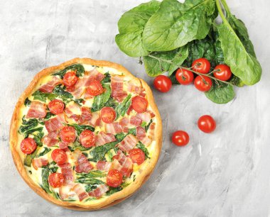 Klasik Fransız pasta kish. Krema, tavuk yumurtası, ıspanak ve pastırma ile dolum. Çerçevepeçende, yumurtalarda. bıçak ve kiraz domates. Yukarıdan görüntüleyin. Close.