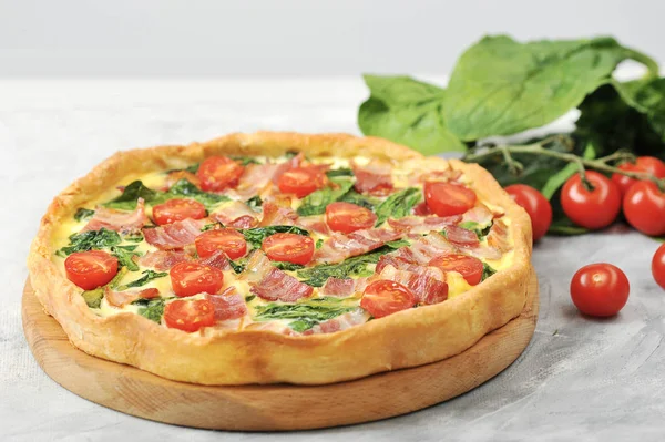 Klasik Fransız pasta kish. Krema, tavuk yumurtası, ıspanak ve pastırma ile dolum. Çerçevepeçende, yumurtalarda. bıçak ve kiraz domates. Close.