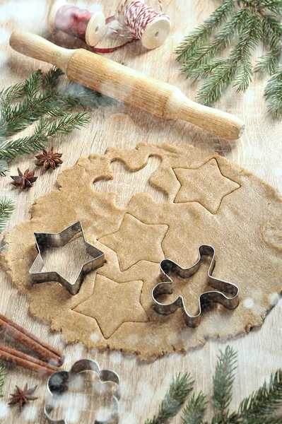 Noel kurabiyeleri pişiriyorum. Hamur ve kurabiye kesiciler. Ladin dalları, tarçın, anason kompozisyonu tamamlar. Dikey çerçeve yönlendirmesi. Açık arka plan.