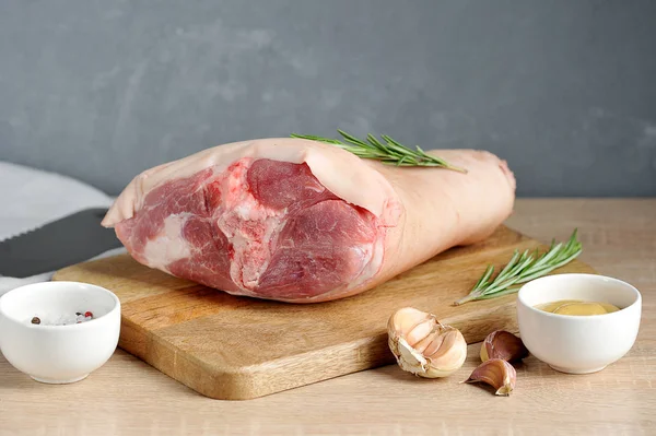 Domuz knob ahşap bir tepside ham. Çerçeve hardal, sarımsak, biberiye, yemek için baharat. Açık gri arka plan. Close.