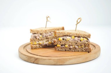 Sandviçler şişlerle sabitlenir. Sandviçin dolgusu mısır ve ton balığından oluşur. Close. Açık arka plan.