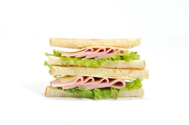 Beyaz bir arka plan üzerinde üçgen şekilli sandviç. Sandviçin dolgusu marul, jambon, peynir ve taze sebzelerden oluşmaktadır. Close.