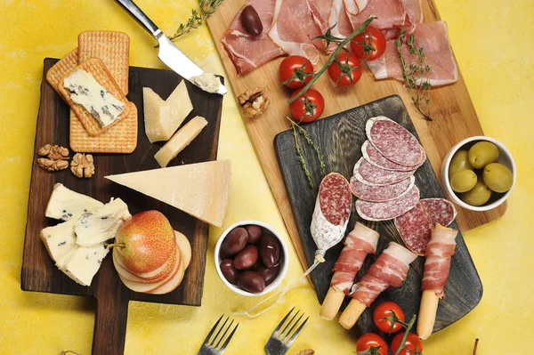Atıştırmalık seti. Küflü peynir, Parmesan parçaları, kraker, fındık ve armut. Salam, pastırma, Parma jambonbaşka bir tahta dilimleri üzerinde. Sonraki fincanlar zeytin, çeri domates. Yukarıdan görüntüle.