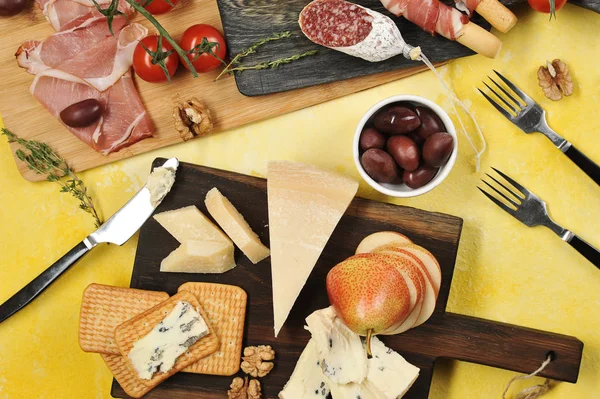 Atıştırmalık seti. Küflü peynir, Parmesan parçaları, kraker, fındık ve armut. Salam, pastırma, Parma jambonbaşka bir tahta dilimleri üzerinde. Sonraki fincanlar zeytin, çeri domates. Yukarıdan görüntüle.