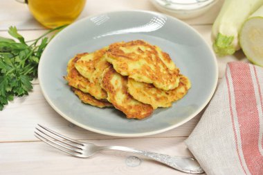 Tabaktaki sebze iliğinden krep. Tabağın yanında peçete, çatal, taze otlar ve kabak var. Açık ahşap arka plan. Close. Makro fotoğrafçılık.