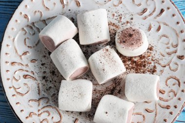 Kahverengi desenli bir tabak üzerinde büyük marchmelow. Çikolata çekirdekli marshmelow beyaz. Yukarıdan görüntüleyin. Close. Makro fotoğrafçılık.