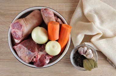Et jölesi yapmak için bir set. Bir kapta, domuz eklemi ve sığır gümüş tarafı, havuç, soğan. Defne yaprağı, sarımsak, biberli bir sonraki tabak. Ahşap arka plan. Yukarıdan görüntüleyin. Close.