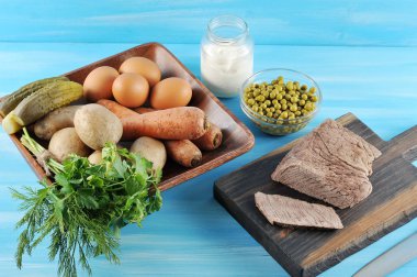 Salata olivier hazırlanması için ayarlayın. Tabakta haşlanmış yumurta, patates, havuç, salatalık turşusu, yeşillik. Mayonez konservesinin yanında, bir tabak yeşil bezelye ve haşlanmış sığır eti. Close.