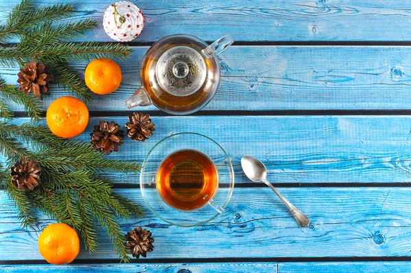 Noel kompozisyonu. Ladin dalı mandalina, koni ler ile dekore edilmiştir. Çay ve bir fincan ve tabak ile bir çaydanlık kompozisyon tamamlayın. Mavi arka plan. Close. Yukarıdan görüntüle.