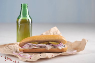 Ringa balığı, soğan ve salatalık turşusu ile geleneksel Hollanda sandviç. Arka planda bir şişe bira. Açık arka plan. Close. Makro çekimi.