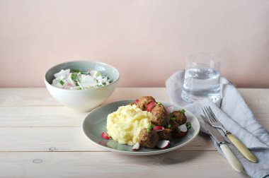 Köfte, turp ve yeşil soğan ile patates püresi. Bir kapta, ekşi kremalı sebze salatası. Geleneksel İskandinav yemeği. Açık arka plan.