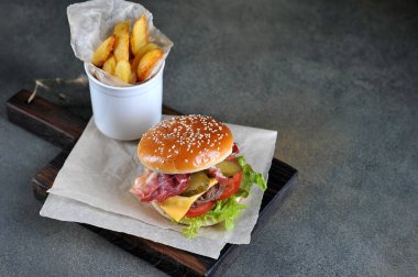 Pastırma ve Idaho patates yakın çekim ile Cheeseburger. Karanlık arka plan. Metni yerleştirmek için boş alan.