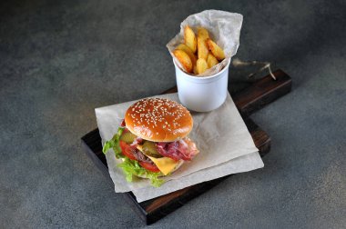 Pastırma ve Idaho patates yakın çekim ile Cheeseburger. Karanlık arka plan. Metni yerleştirmek için boş alan.