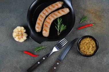 Izgara domuz sosisi. Hardal bir fincan, biberbiber, biberiye ve sarımsak kompozisyon tamamlayın. Karanlık arka plan. Close. Yukarıdan görüntüle.