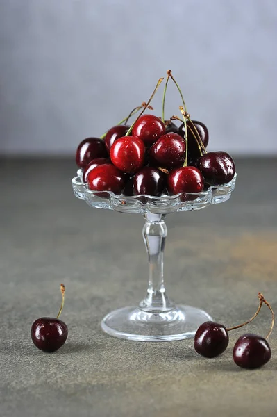 Cherry berries in a glass vase. Drops of water are visible on the berries of ripe sweet cherry. Close-up. Vertical frame orientation.