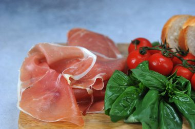 Antipasto prosciutto, baget dilimleri, çeri domates. Bir demet taze fesleğen. Açık arka plan. Close.