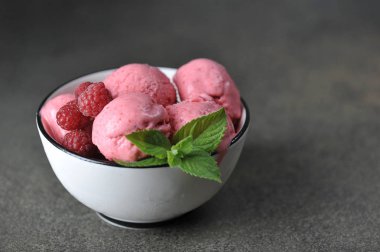 Meyveli dondurma topları ile Fincan. Dondurma taze ahududu ve nane yaprakları ile dekore edilmiştir. Close. Karanlık arka plan. Metni yerleştirmek için boş alan.