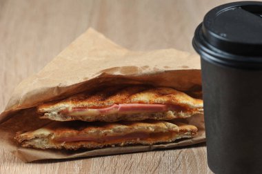 Jambon ve peynirli sandviç ve kahveli kağıt bardak. Fast food ve kahve kavramı gitmek. Close. Açık arka plan. Metin için boş alan.